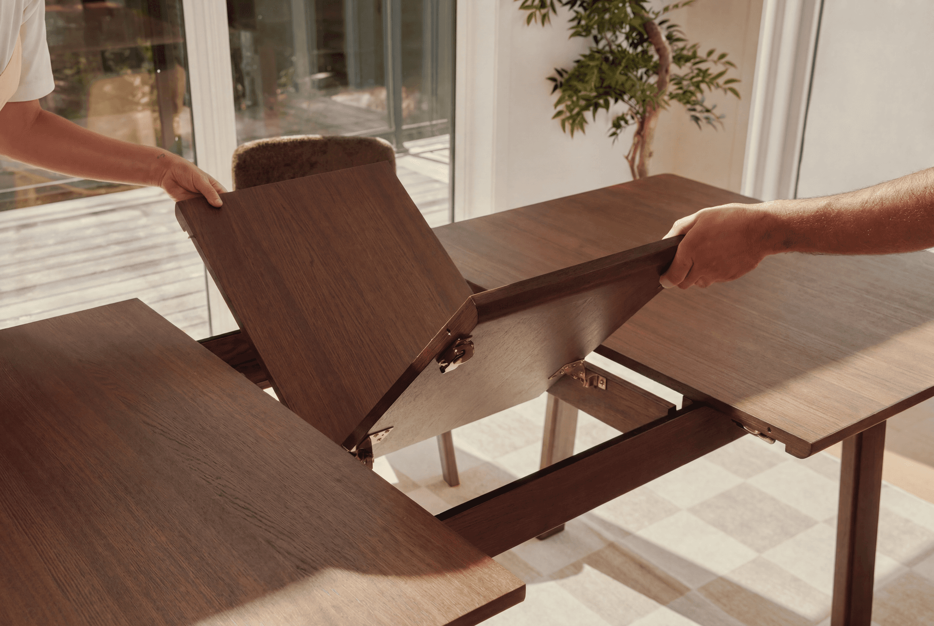 Opening the extension leaf on a walnut Vela dining table