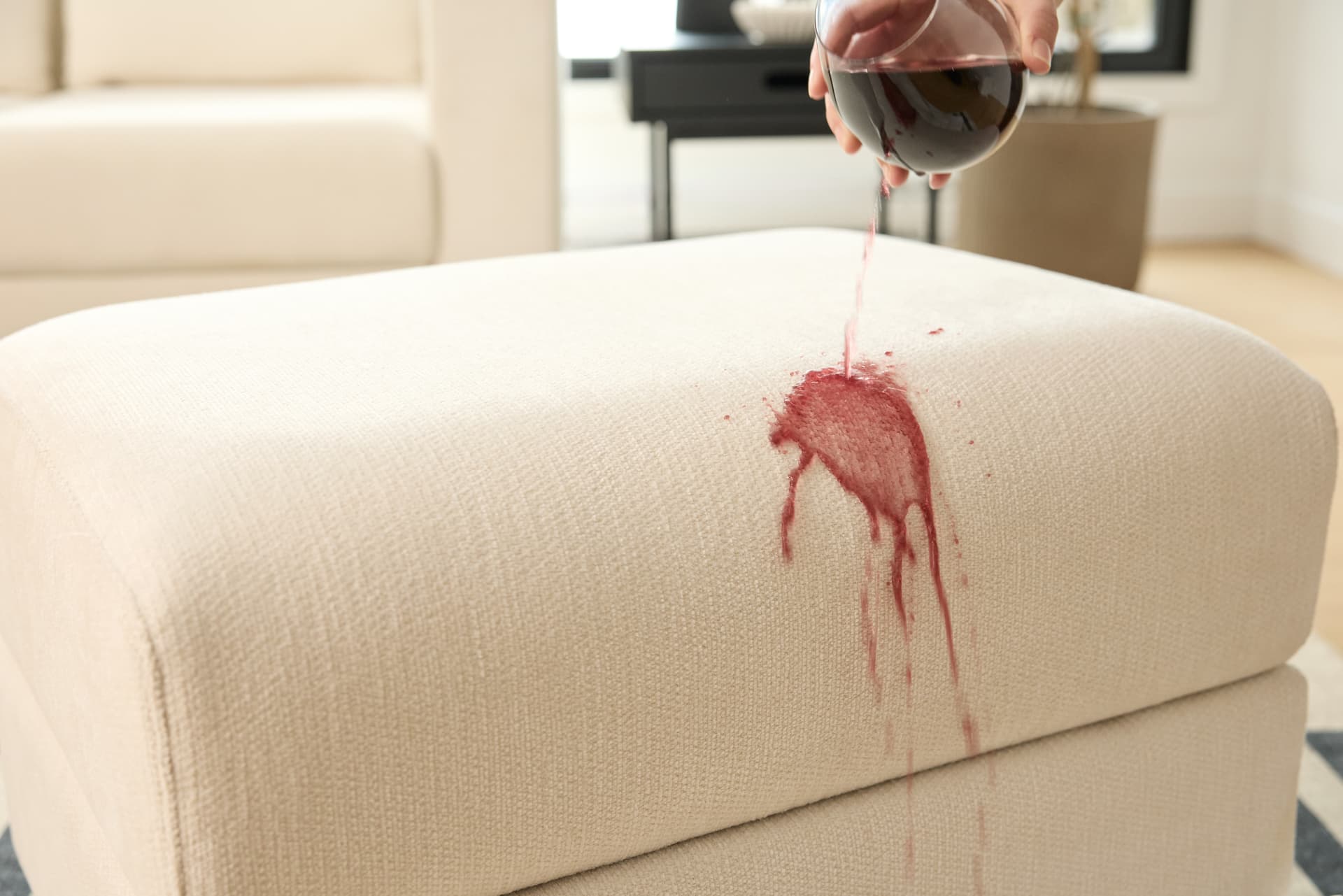 A glass of wine being spilled on a Cozey sofa